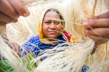 A female worker observes sun-dried pineapple leaf fibers with her hands. Closeup views. Agricultural waste product.