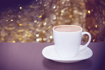 White cup of coffee with milk, lights glittering bokeh. Celebrate, Christmas, New Year, holiday party background.