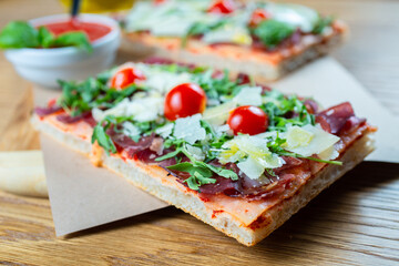 pizza with cherry tomatoes, parmesan cheese, arugula and smoked ham