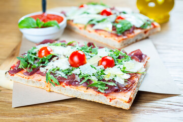 pizza with cherry tomatoes, parmesan cheese, arugula and smoked ham