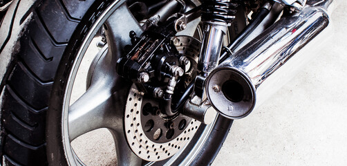 Back of sports bike close-up in garage. Wheel, brake disc, exhaust pipe, transmission, shock...