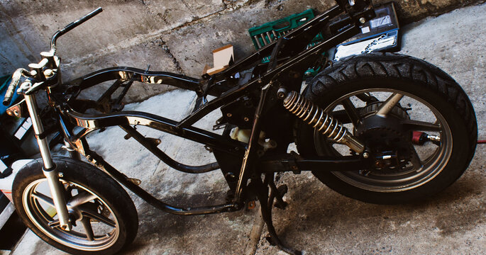 Frame of motorcycle, wheels without skin tank and motor. Disassembled motorbike on parts, in  workshop on concrete. Professional mechanic tool kit for repairing vehicles in garage Banner for web site