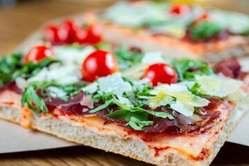 pizza with cherry tomatoes, parmesan cheese, arugula and smoked ham