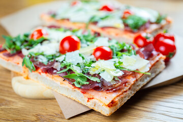 pizza with cherry tomatoes, parmesan cheese, arugula and smoked ham