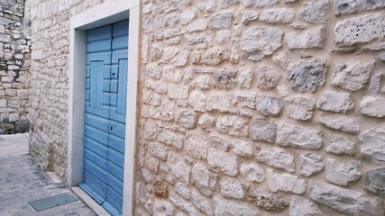 Niebieskie drewniane drzwi w kamiennym murze