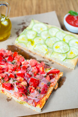 Pizza with tomato, ham, pesto and zucchini