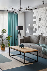 Modern Living Room .Grey sofa and cyan blanket,carpet and curtains.Decorative honeycomb on the wall.Modern floor lamp. Design interior. Grey,white cyan colors.Closeup.