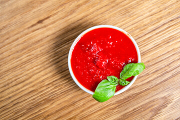 tomato sauce with fresh basil on a wooden background