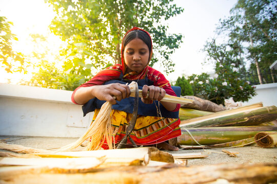 A woman worker is cutting the bark from the trunk of a banana tree to make fibers. Rubber fiber of banana tree. Agricultural waste product.