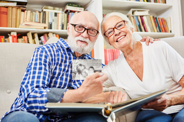 Glückliches altes Ehepaar schaut sich Fotos an