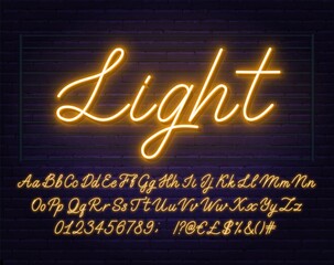 Neon yellow script font. Glowing alphabet with letters, numbers and special characters on a brick background.