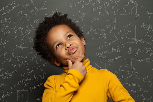 Clever Black Child Thinking On Chalkboard Background With Science Formulas