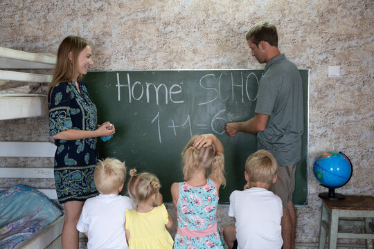 Parents teach their children at the blackboard in their home. Home school.