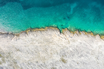 Top view drone aerial of coastal cliff rock formation above ocean