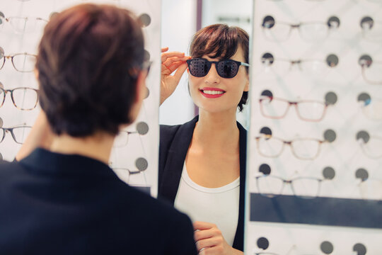 a woman tries on sunglasses in a glasses store