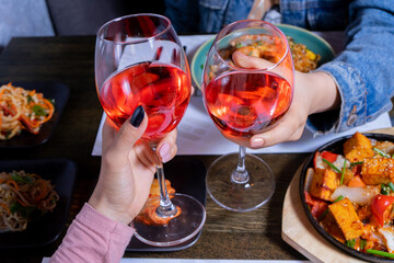 Cheers with wine glasses and asian food