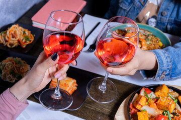 Cheers with wine glasses and asian food