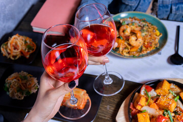 Cheers with wine glasses and asian food