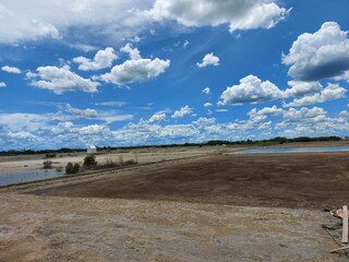 Beautiful clouds on clear blue sky reflecting on salt farm water below in rural area of Thailand