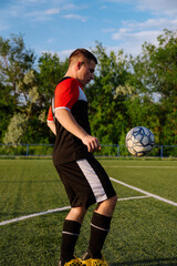 Young male soccer player juggles a ball on a soccer field