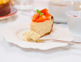 Fresh strawberry cheesecake on a ceramic plate on a white festive table