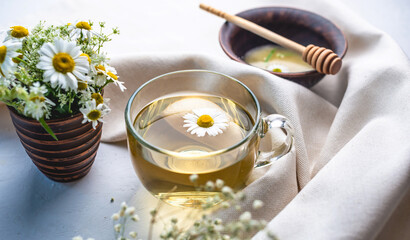 Transparent cup of hot chamomile tea and honey. Concept of a healthy soothing herbal drink after a hard day or in the morning