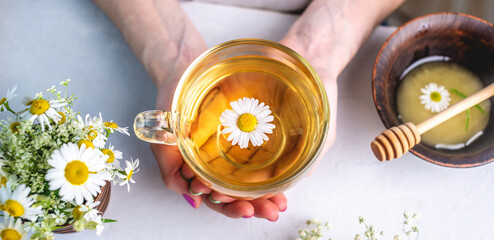 Transparent сup of hot chamomile tea and honey. Concept of a healthy soothing herbal drink after a hard day or in the morning