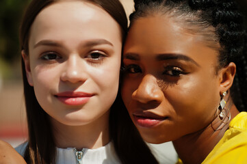 Close up faces of white caucasian girl and black African American together. World unity, racial...