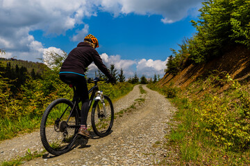 Fototapeta premium Cycling woman on mtb bike on gravel mountain road, Beskidy, Poland.