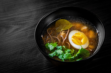 Japanese ramen soup with tofu and egg on black wooden table background
