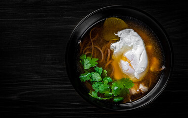 Japanese ramen soup with tofu and egg on black wooden table background