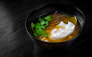 Japanese ramen soup with tofu and egg on black wooden table background