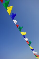 Bright colorful buddhist Prayer flags on clear blue sky background. Multi colored Prayer flags in...
