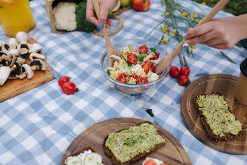 Woman mix vegan salad on picnic outside. Vegan food concept