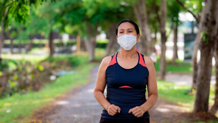 Portrait of Asia woman wearing mask jogging in the park