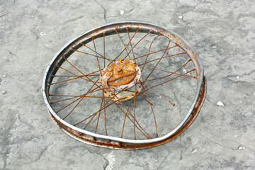 Fototapeta na wymiar Alte, verbogene und rostige Fahrradfelge auf felsigem Hintergrund.
