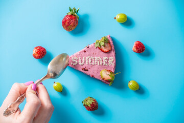Piece of pink mousse cake with the word Summer made up of small flowers. Concept of summer mood and bright desserts. Blue background