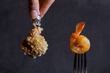 Shrimp on a fork and crispy chicken on black background