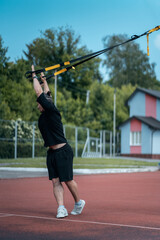 Fototapeta na wymiar young sporty athlete or bodybuilder has fitness workout with trx outdoor