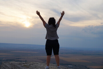 Obraz premium middle-aged woman of Asian appearance stands on top holding her hands up in ecstasy