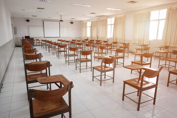 Fototapeta na wymiar Empty classroom with vintage tone wooden chairs. Classroom arrangement in social distancing concept to prevent COVID-19 pandemic. Back to school concept. 