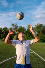 Young male soccer player juggles a ball with his head on a soccer field © bo.kvk