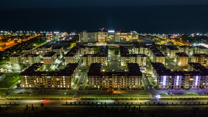 Night city. Evening lighting of the building. Residential area of the city. Sochi Olympic Park. Sunset. Multi-storey building.