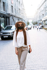 Young woman in medical mask is walking around the city. Protecting from allergy, virus, smog