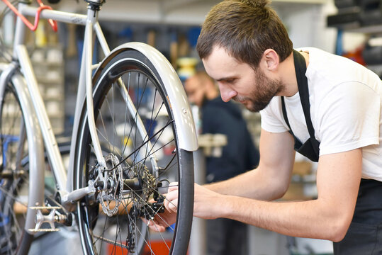 friendly and competent bicycle mechanic in a workshop repairs a bike