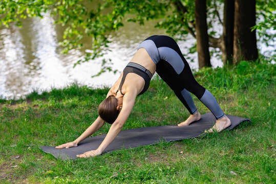 girl doing yoga pose dog face down outdoors in summer