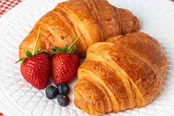 Fresh croissant decorated with berries on white wooden board