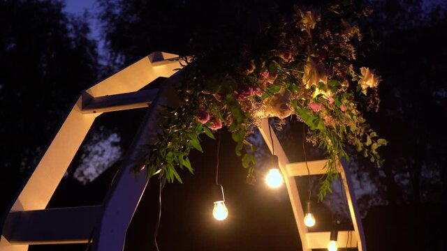 4k video footage of beautiful place made with wooden circle ring construction and floral decorations for outside wedding ceremony in wood in romantic darkness of night.