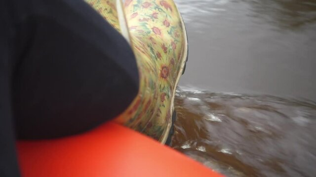 River rafting in summer. Packrafting in wilderness. A leg in a rubber boot overboard. Derzha River, Tver Region, Russia.