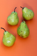 Over ripe green delicious pear against orange background. Zero waste and organic food concept
